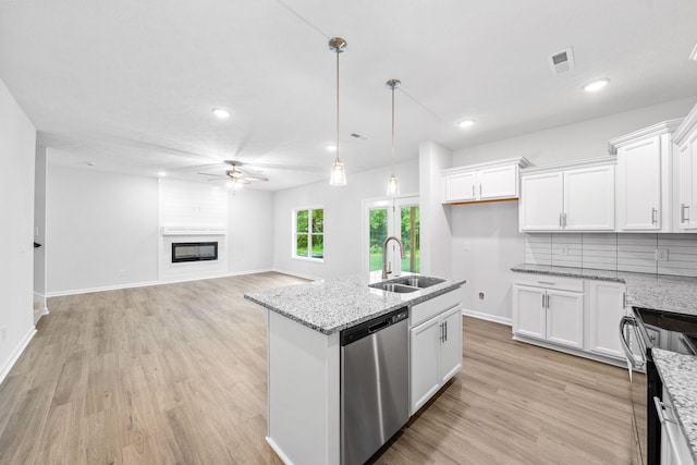 kitchen with light stone countertops, sink, white cabinets, and stainless steel dishwasher