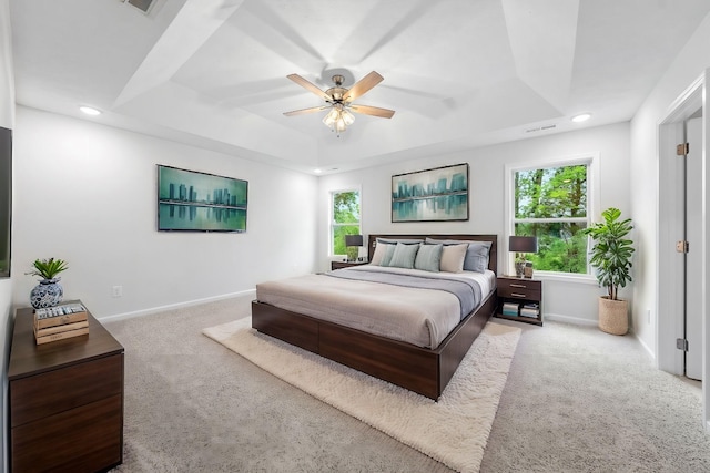 bedroom featuring a raised ceiling, ceiling fan, and light colored carpet