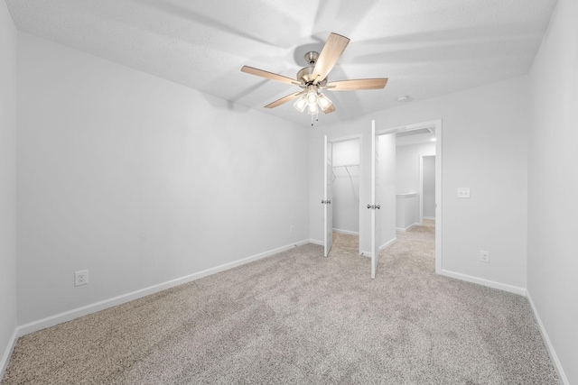 unfurnished bedroom featuring ceiling fan, light colored carpet, a spacious closet, and a closet