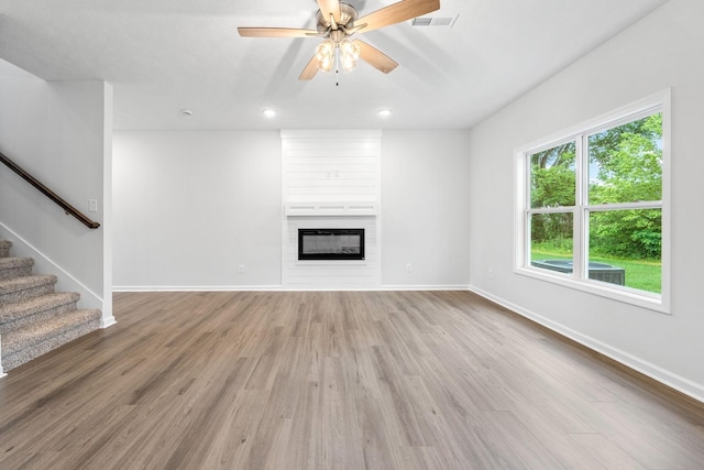 unfurnished living room with hardwood / wood-style floors, ceiling fan, and a large fireplace