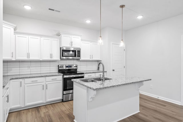 kitchen featuring sink, white cabinets, stainless steel appliances, and a center island with sink