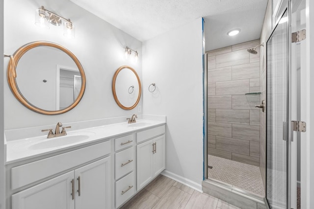 bathroom featuring vanity, a shower with shower door, and a textured ceiling