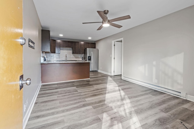 kitchen with decorative backsplash, stainless steel fridge, light wood-type flooring, dark brown cabinets, and kitchen peninsula