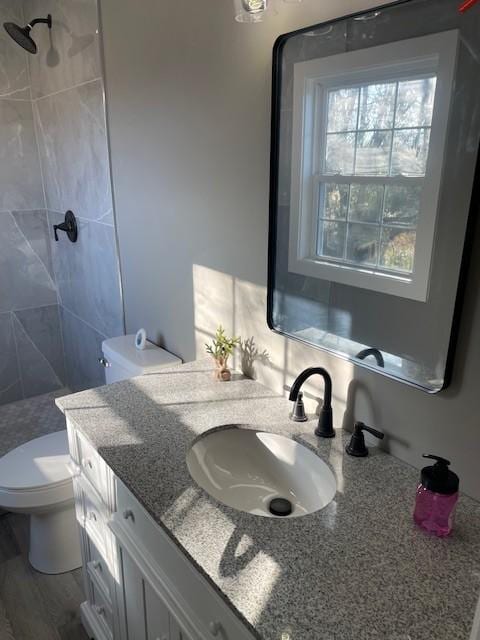 bathroom with vanity, toilet, and a tile shower