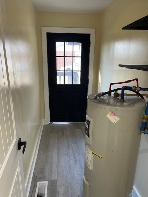 doorway to outside with water heater and dark hardwood / wood-style flooring