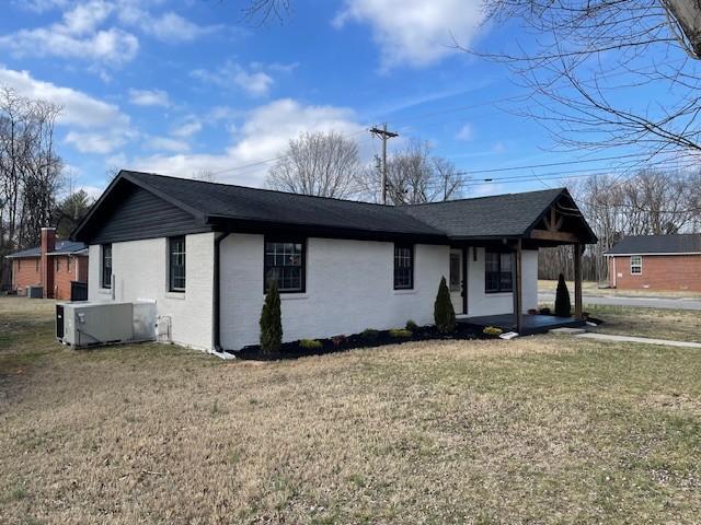 view of front of home with central AC unit and a front lawn