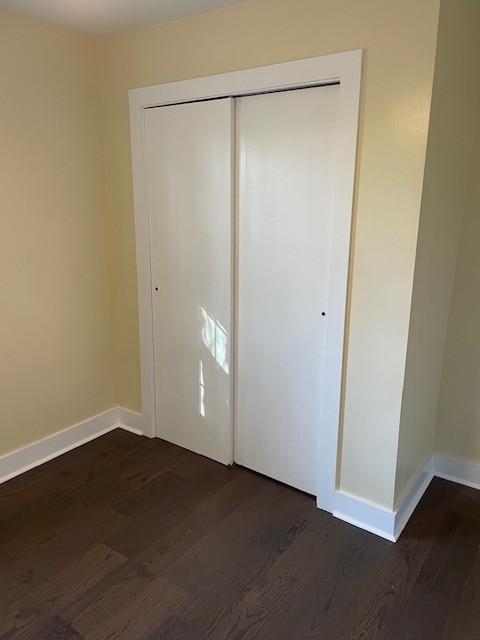 unfurnished bedroom with dark wood-type flooring and a closet