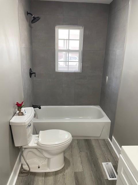 full bathroom featuring vanity, hardwood / wood-style flooring, tiled shower / bath combo, and toilet