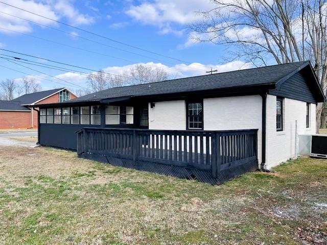 back of house with a wooden deck, central AC unit, and a lawn