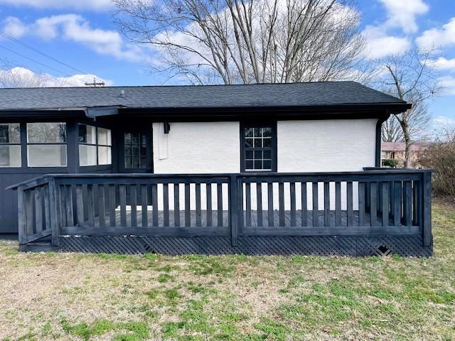 back of house with a lawn and a deck