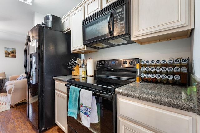 kitchen featuring dark wood-type flooring, dark stone counters, and black appliances