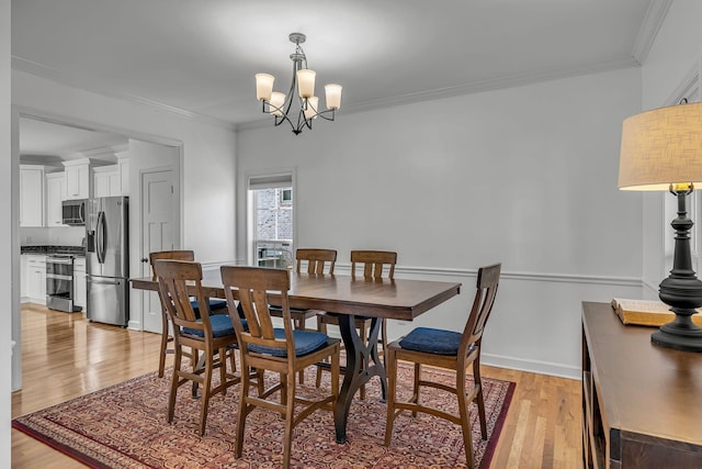 dining room with crown molding, light wood-type flooring, and a notable chandelier