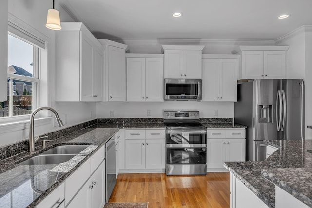 kitchen with sink, white cabinets, hanging light fixtures, and appliances with stainless steel finishes