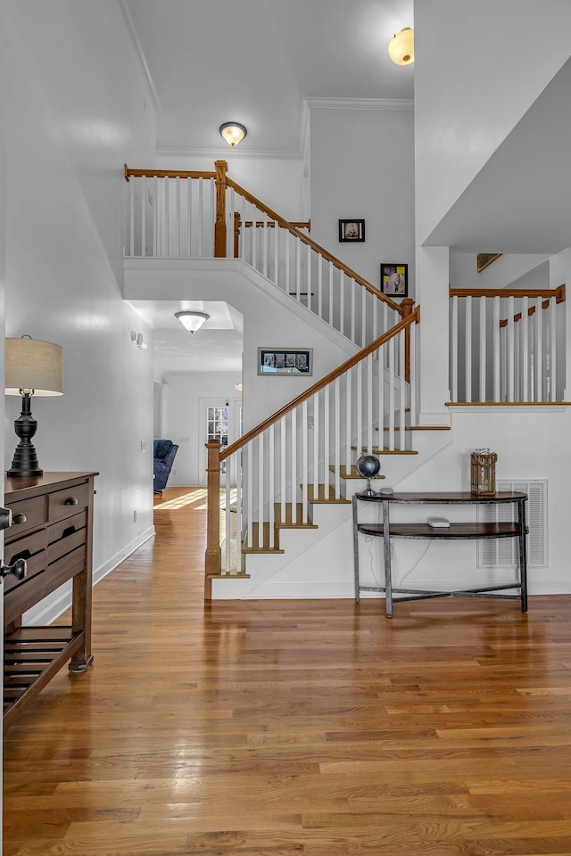 staircase with hardwood / wood-style flooring, ornamental molding, and a towering ceiling