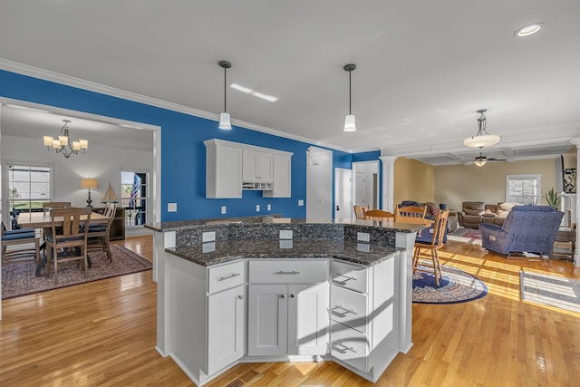 kitchen featuring white cabinetry, hanging light fixtures, and dark stone counters