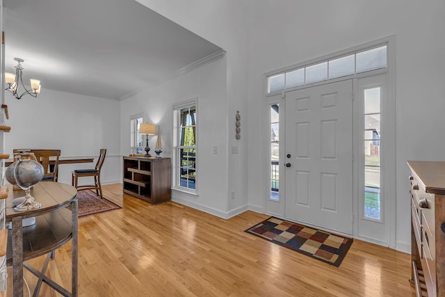 entrance foyer with ornamental molding, light hardwood / wood-style floors, and an inviting chandelier