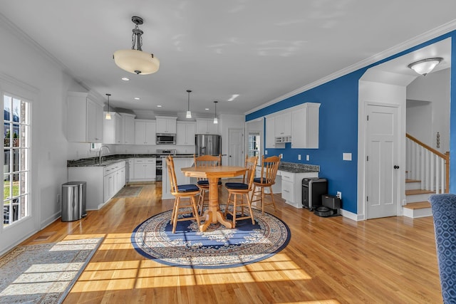 dining area featuring light hardwood / wood-style floors, ornamental molding, and sink