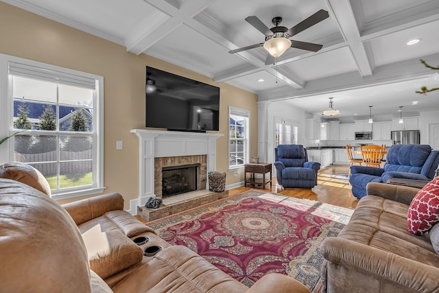 living room with a tile fireplace, light hardwood / wood-style floors, plenty of natural light, and coffered ceiling