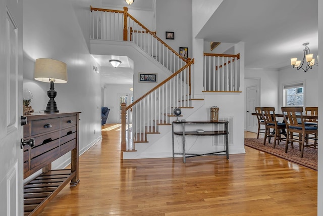 foyer entrance featuring light hardwood / wood-style floors, ornamental molding, and an inviting chandelier