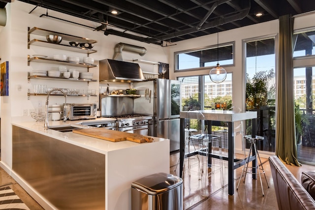 kitchen with hanging light fixtures, kitchen peninsula, high end stainless steel range oven, and extractor fan