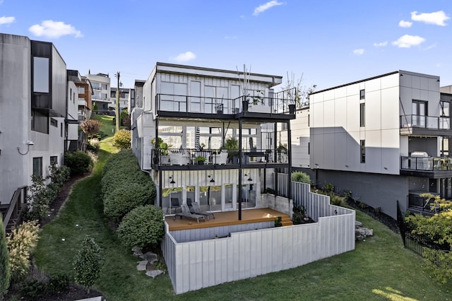 rear view of property featuring a balcony and a lawn