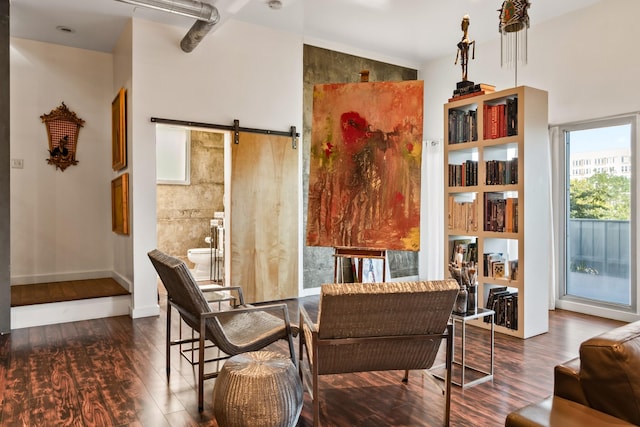 living area featuring a barn door, dark hardwood / wood-style floors, and a wealth of natural light