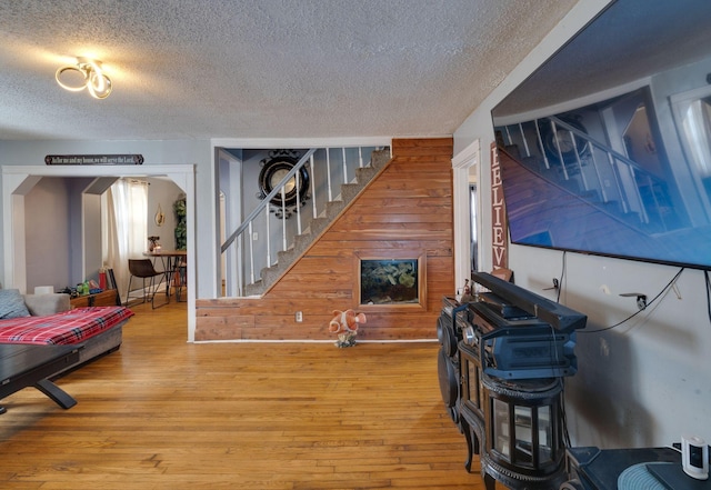 living room with hardwood / wood-style flooring, a textured ceiling, and wooden walls