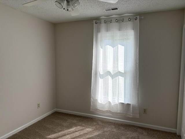 carpeted spare room with ceiling fan and a textured ceiling