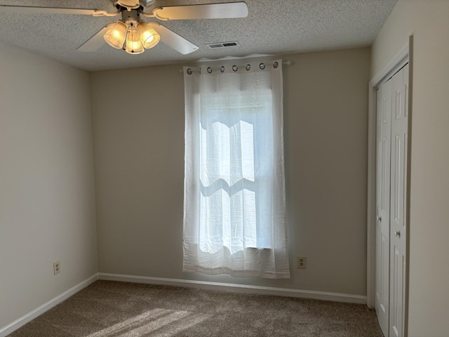 carpeted spare room featuring ceiling fan and a textured ceiling