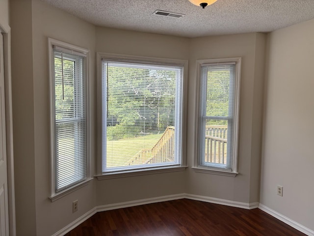 unfurnished room with dark hardwood / wood-style flooring and a textured ceiling