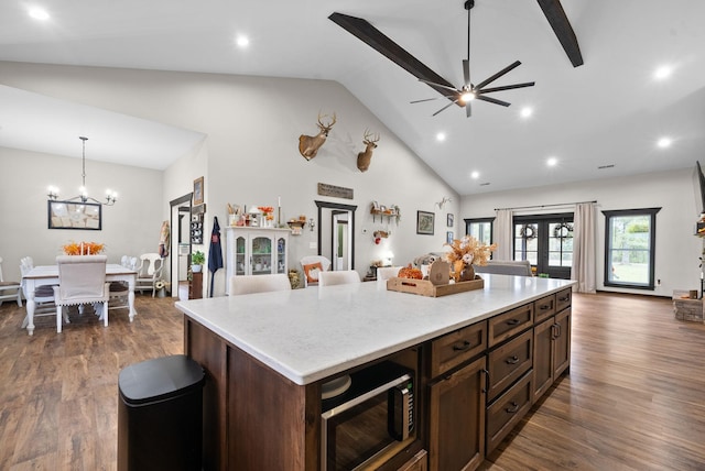 kitchen with built in microwave, decorative light fixtures, a kitchen island, dark hardwood / wood-style flooring, and dark brown cabinets