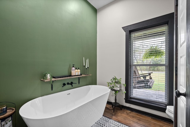 bathroom with a bathing tub, toilet, and hardwood / wood-style floors