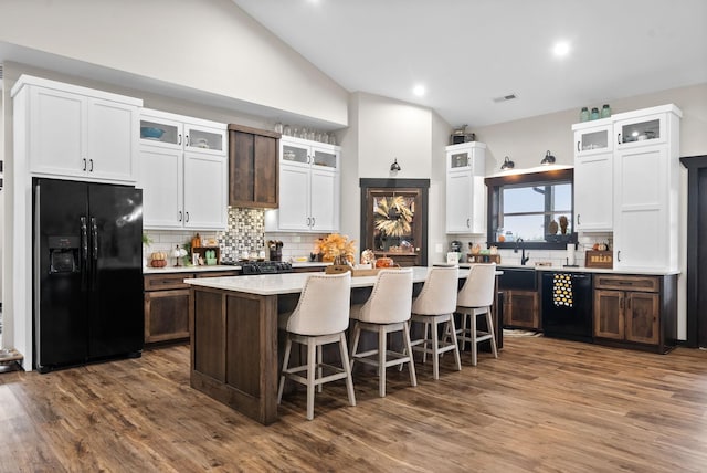 kitchen with white cabinetry, a center island, dark wood-type flooring, a breakfast bar, and black appliances