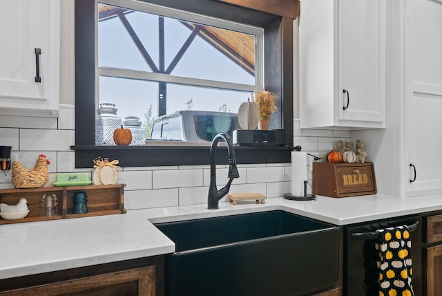 kitchen featuring white cabinetry, decorative backsplash, sink, and black dishwasher