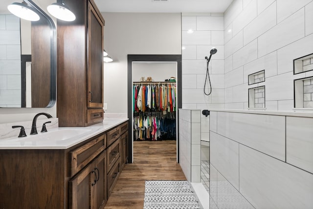 bathroom with hardwood / wood-style floors, vanity, and tiled shower