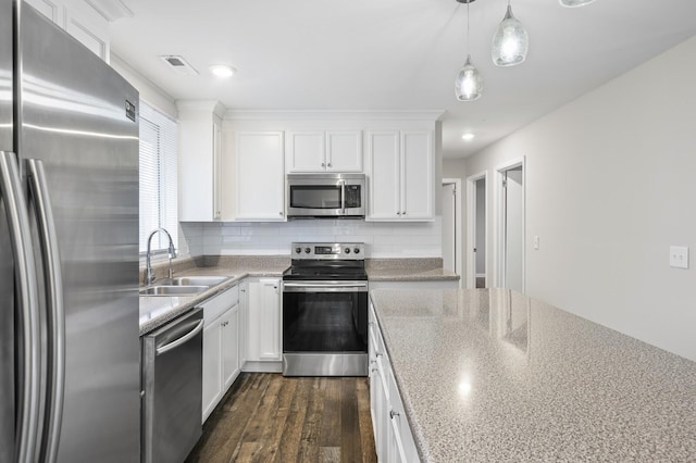 kitchen with backsplash, stainless steel appliances, sink, white cabinetry, and hanging light fixtures