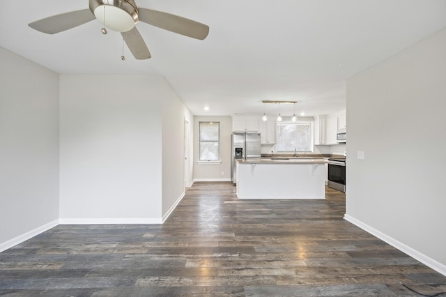 unfurnished living room featuring ceiling fan, dark wood-type flooring, and sink