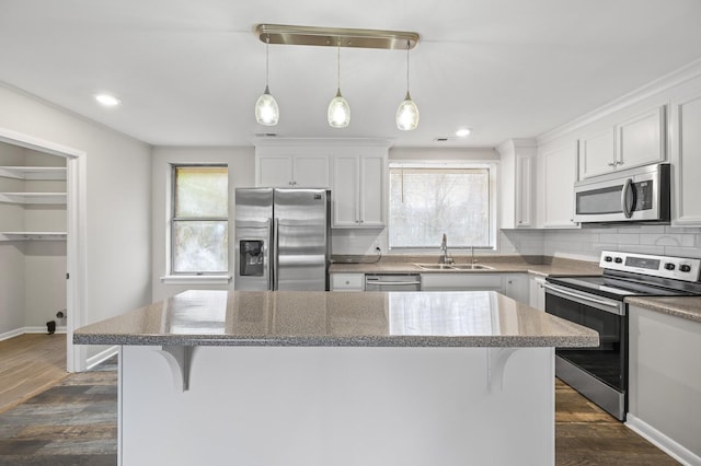 kitchen featuring a breakfast bar, white cabinets, sink, decorative light fixtures, and stainless steel appliances