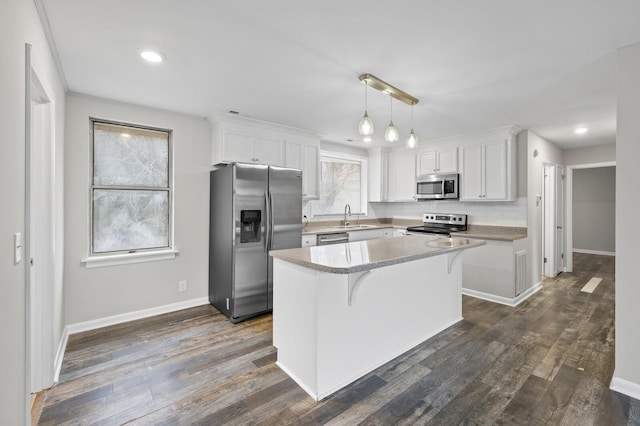 kitchen featuring white cabinets, appliances with stainless steel finishes, a center island, and decorative light fixtures