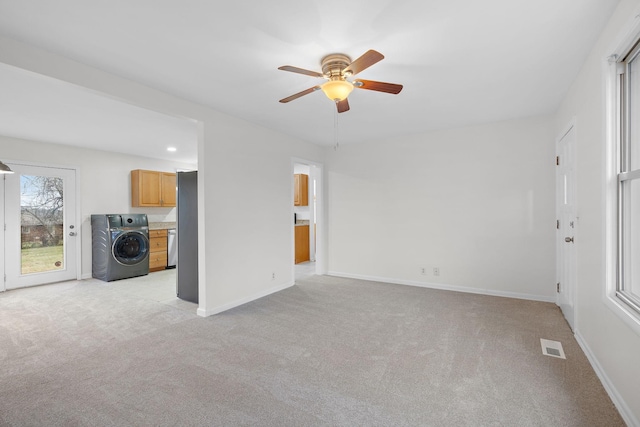 unfurnished living room with washer / clothes dryer, light carpet, and ceiling fan