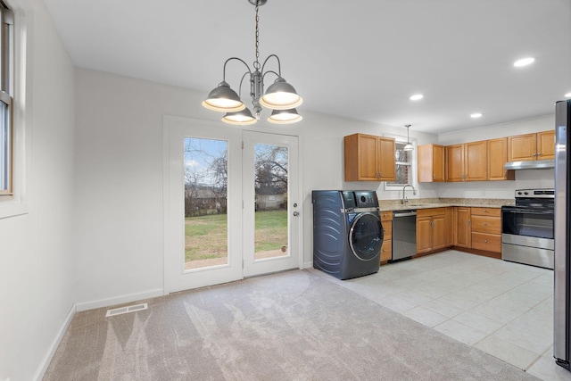 kitchen with washer / dryer, stainless steel appliances, hanging light fixtures, and sink