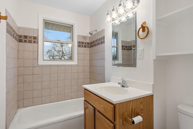 full bathroom featuring tiled shower / bath, vanity, and toilet