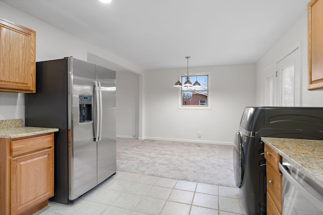 kitchen featuring light stone countertops, light colored carpet, pendant lighting, washer / dryer, and appliances with stainless steel finishes