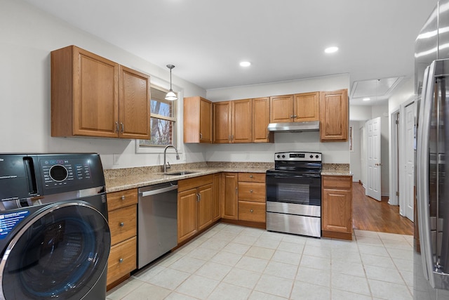 kitchen with sink, stainless steel appliances, light stone counters, decorative light fixtures, and washer / dryer