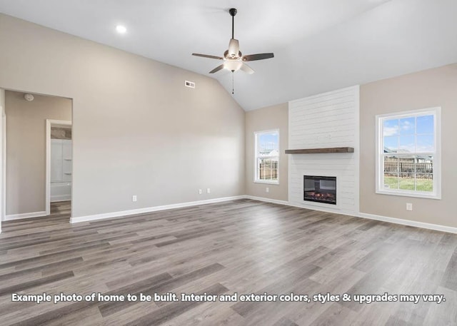 unfurnished living room with ceiling fan, a large fireplace, light hardwood / wood-style floors, and a wealth of natural light