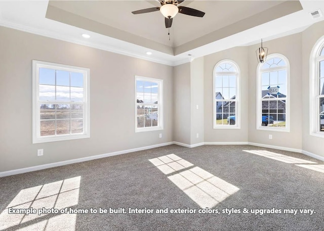 carpeted spare room with ceiling fan with notable chandelier, a tray ceiling, and ornamental molding