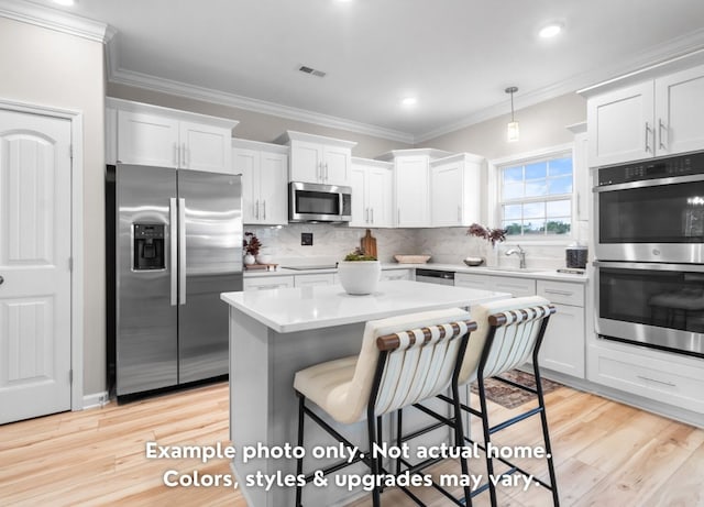 kitchen with pendant lighting, tasteful backsplash, white cabinets, ornamental molding, and stainless steel appliances