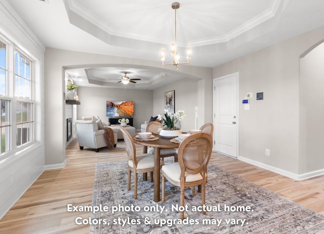 dining space featuring crown molding, a tray ceiling, light hardwood / wood-style floors, and a chandelier