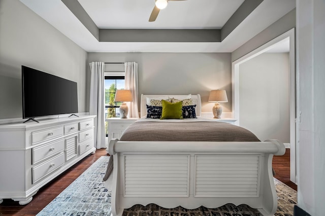 bedroom featuring a raised ceiling, ceiling fan, and dark hardwood / wood-style flooring