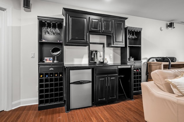 bar featuring refrigerator, dark hardwood / wood-style floors, and sink